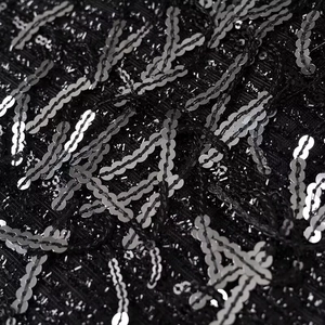 Macro shot of silver sequins on black mesh fabric for this sparkling mini dress
