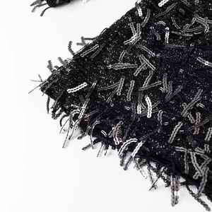 Macro view of black sequin fabric and fringe details on the festive mini dress
