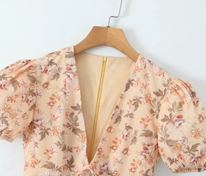 Dettaglio vestito floreale con maniche a sbuffo, scollo a V e zip dorata sul retro