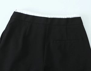 Detail einer minimalistischen schwarzen Hose mit einem schwarz-weißen Patchwork-Bunddesign