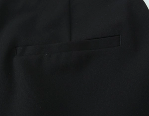 Detailansicht der Taschennaht und feinen Köpertextur auf einer schwarzen Hose