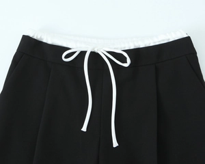 Detail der Kontrast-Taille mit weißem Kordelzug an schwarzer Patchwork-Hose