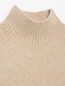 Détail d'un pull en maille beige montrant le col montant et la texture côtelée