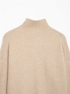 Détail du col roulé côtelé et des épaules tombantes sur le pull en maille couleur avoine