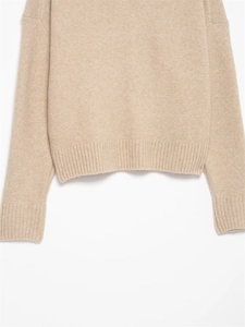 Détail des poignets et de l'ourlet côtelés sur un pull en maille beige et doux
