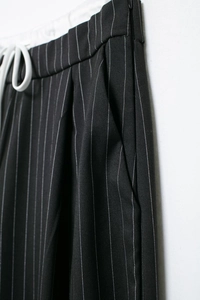 Details von gestreifter schwarzer Hose mit elastischem Bund, weißem Kordelzug und Seitentaschen