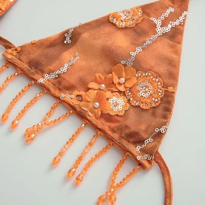 Détail du haut de bikini orange avec broderie florale, paillettes et franges de perles