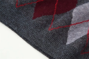 Macro detail of the soft knit texture and Argyle diamond pattern in grey and burgundy