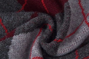 Macro view of argyle knit fabric with soft gray and red yarn fibers and texture detail