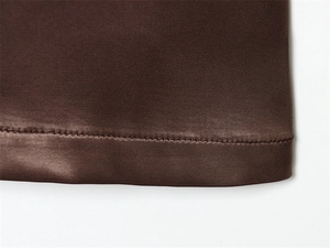 Gros plan de l'ourlet en satin de soie marron foncé avec couture précise à double aiguille
