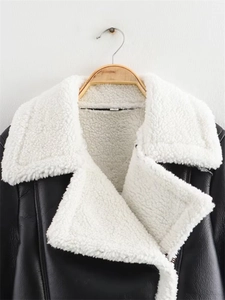 Detail of black faux leather biker jacket with soft white shearling lining and collar