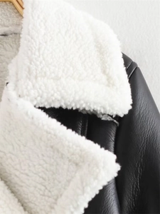 Close-up of black faux leather jacket with white shearling lining and collar detail