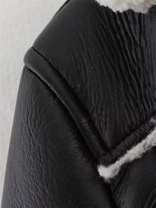 Detail of premium black leather jacket showing white faux fur lining and stitching