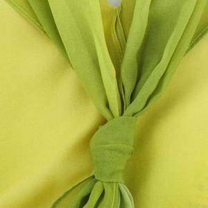 Detailed macro view of the knotted chiffon fabric and floral texture on a lime green dress