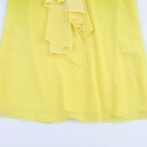 Close-up of bright yellow semi-transparent pleated chiffon fabric with ruffled details