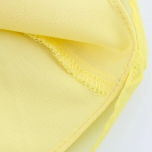 Macro view of stitching and hem details on the yellow floral chiffon halter dress