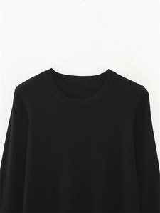 Detail of classic black long-sleeve crewneck knit top with fine texture on white background