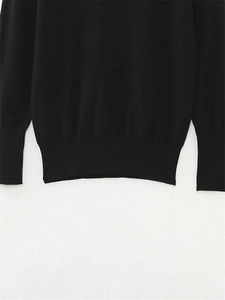 Detailed macro view of the black knit sweater showing ribbed hem and sleeve cuffs texture