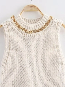 Close-up of white chunky knit sleeveless top with chunky gold chain necklace detail