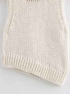 Detailed macro view of white chunky knit texture and asymmetric ribbed hem of the top