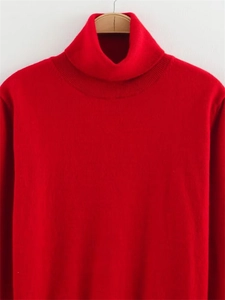 Gros plan d'un pull en maille rouge vif avec col roulé côtelé et texture de tricot fin
