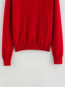 Détail d'un pull en maille rouge avec poignets côtelés et finitions de haute qualité