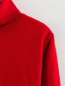 Vue détaillée du col roulé côtelé et de la couture d'épaule de ce pull en maille rouge vif