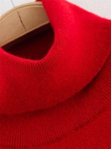 Détail du pull en maille rouge à col roulé épais sur un cintre en bois naturel