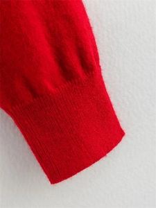 Détail de la manche d'un pull en maille rouge avec texture duveteuse et poignet côtelé