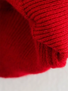 Vue macro détaillée du tissu en maille rouge vif montrant les poignets côtelés et la texture