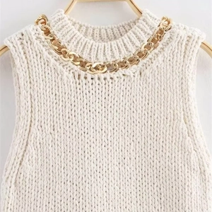White sleeveless knit top featuring round neck and chunky gold chain collar detail