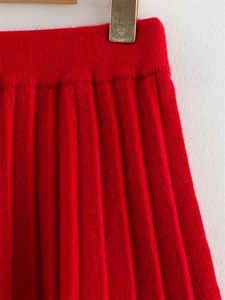 Détail de la texture plissée et de la taille élastique de la jupe rouge en tricot