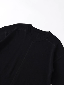 Close-up of crew neck detailing and white contrast stitching on black knit top