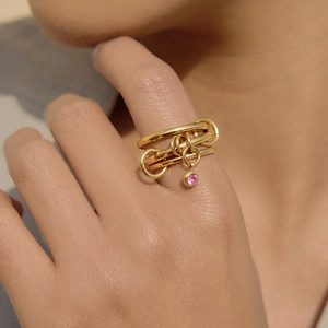 Close-up of a multi-layer gold titanium steel ring with a pink zircon charm