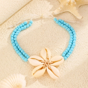 Détail d'un bracelet de cheville bohème avec pierres naturelles et fleur de coquillage