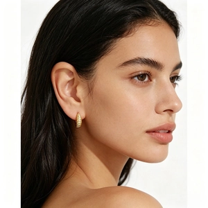Minimalist gold croissant hoop earrings with spiral texture worn by a female model
