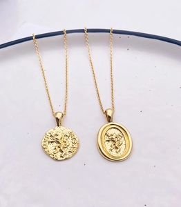 Detail view of lion emblem embossed coin pendants on 18k gold plated chains for women