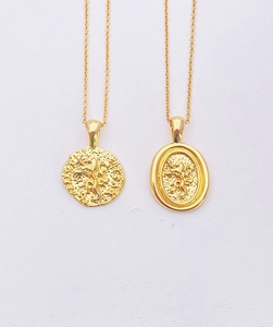 Detail of two vintage 18k gold plated lion coin necklaces with relief engraving