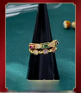 Macro shot of gold-plated rings with emerald, ruby, and sapphire-style gemstone inlays