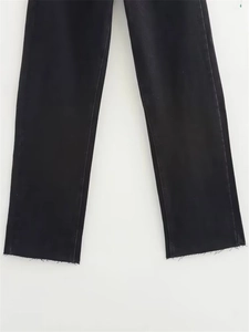 Detail of frayed raw hem edges on stylish black straight-leg denim jeans for women