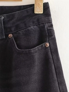 Close-up of charcoal black heavy denim fabric showing reinforced vintage copper rivets
