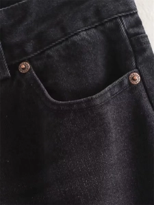 Detail of washed black denim fabric with bronze rivets and pocket stitching