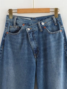Détail de la taille croisée sur un jean large bleu foncé délavé avec deux boutons argentés