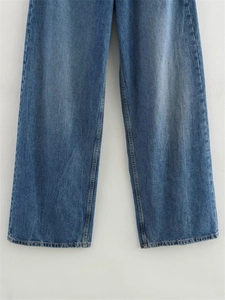 Détail d'un jean large montrant les coutures de l'ourlet et la texture du denim délavé