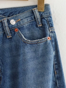 Détail de taille haute sur jean bleu avec fermeture asymétrique originale à double bouton