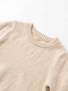 Macro detail of beige crew neck knitwear showing ribbed collar and soft wool texture