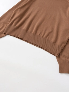 Close-up of warm camel brown wool knit sweater showing ribbed hem and cuff texture detail