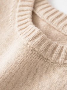 Detailed close-up of a ribbed knit crew neckline on a beige minimalist winter sweater