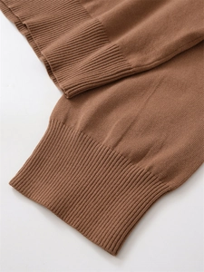 Detailed close-up showing the caramel rib-knit cuffs and fine texture of the wool sweater