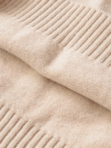 Macro shot of soft cream knit fabric showing fine ribbed edges and premium wool texture